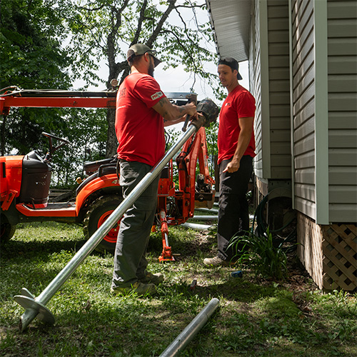 Pro Post Foundations installers installing screw piles with compact equipment