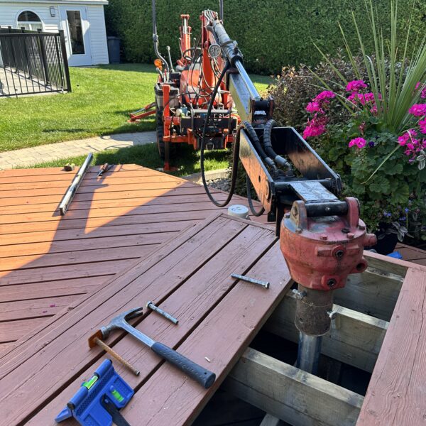 Compact tractor on turf tires with a 270° rotating drive head installing screw piles