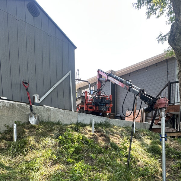 Compact 48 in. wide tractor with a 9 to 14 ft boom reach installing screw piles in a tight space